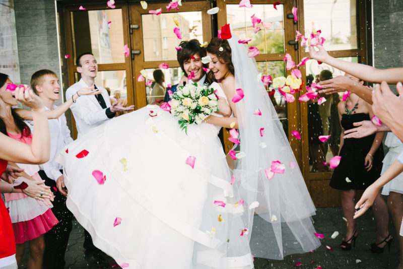 Молодожёны выходят из ЗАГСа, обсыпание лепестками