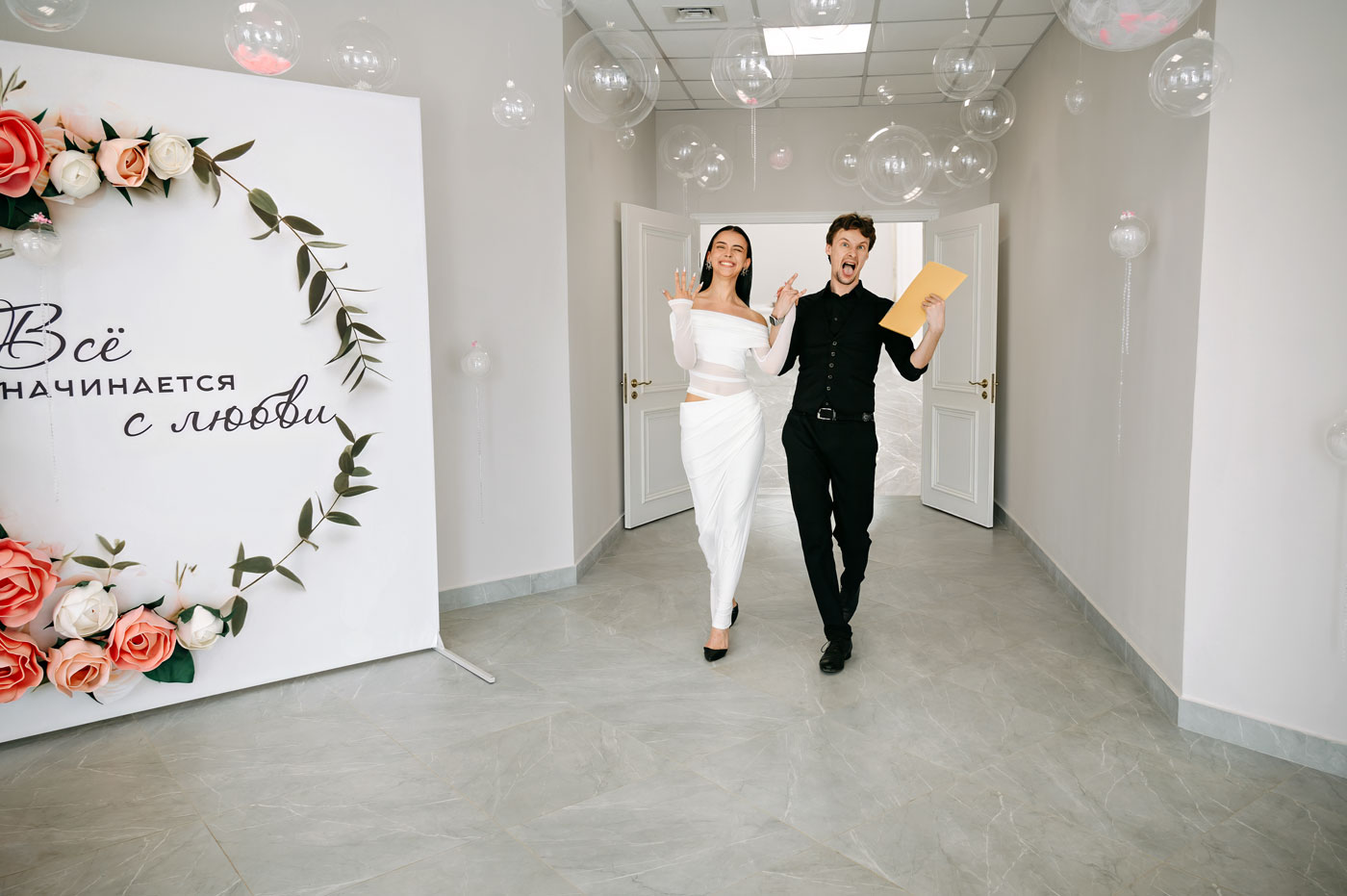 Радостные молодожёны выходят из зала торжественной регистрации