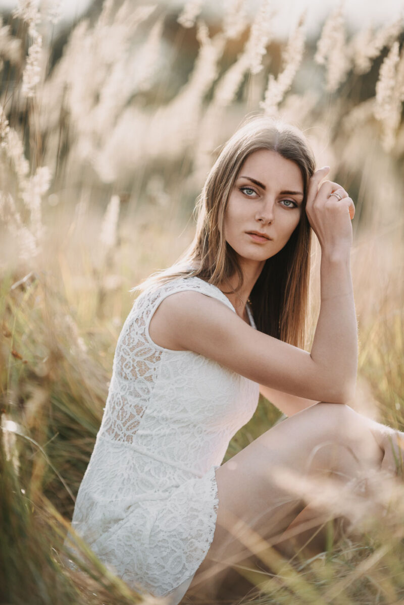 девушка в поле на фоне сухой жёлтой травы в мягком закатном свете, осенняя фотосессия