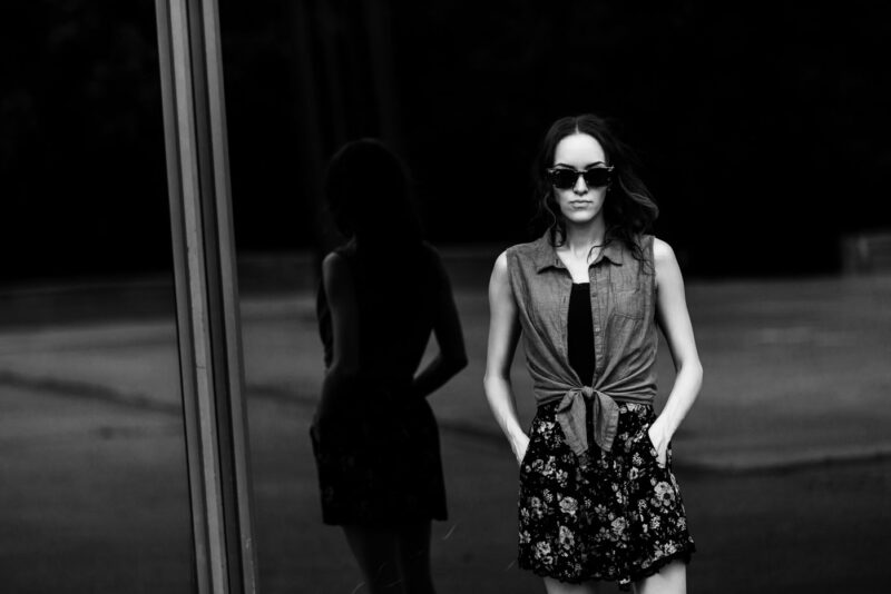 портрет женщины на фоне большого тёмного стекла здания