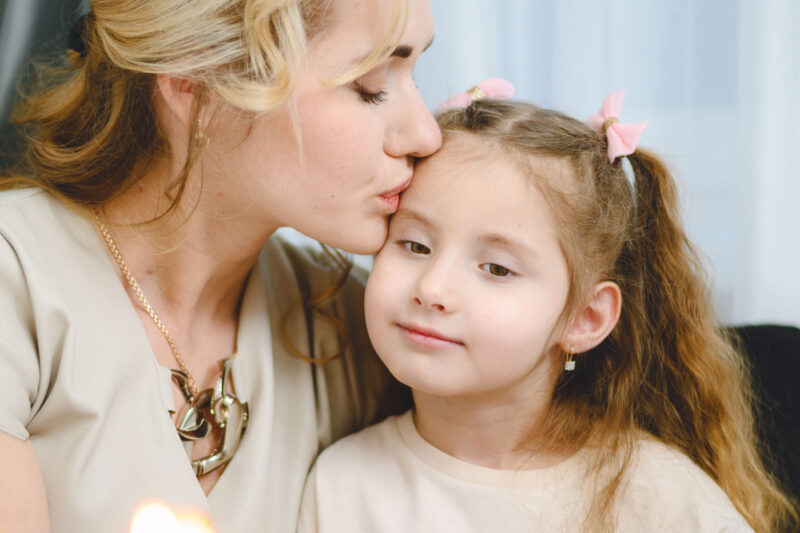 Крупный план мамы, целующей дочку в лоб на семейной съёмке в Ярославле