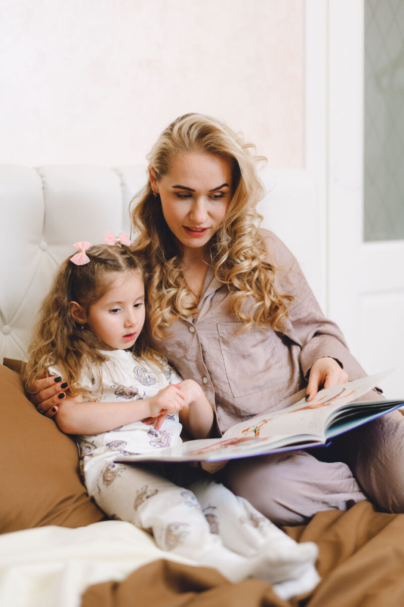 Мама и дочка читают книгу на кровати во время домашней фотосессия в Ярославле