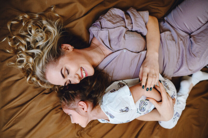 Репортажный портрет крупным планом мамы с дочкой на кровати во время игры