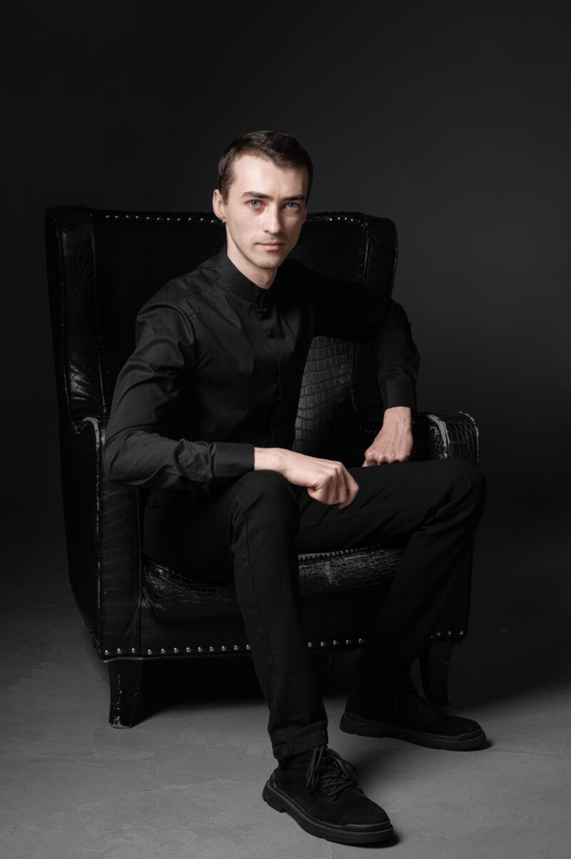 Мужчина сидит в кожаном кресле в тёмной фотостудии Ярославля