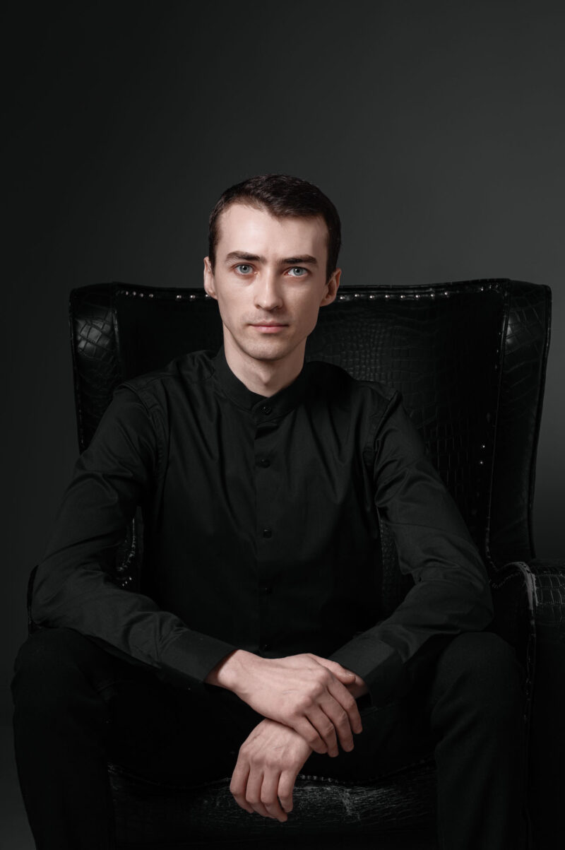 Портрет мужчины в чёрной одежде, сидящего в глубоком кресле