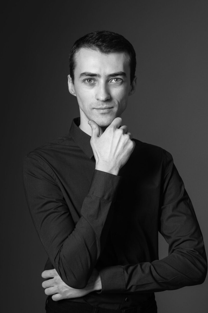 Крупный портрет мужчины с рукой у лица в тёмном зале студии