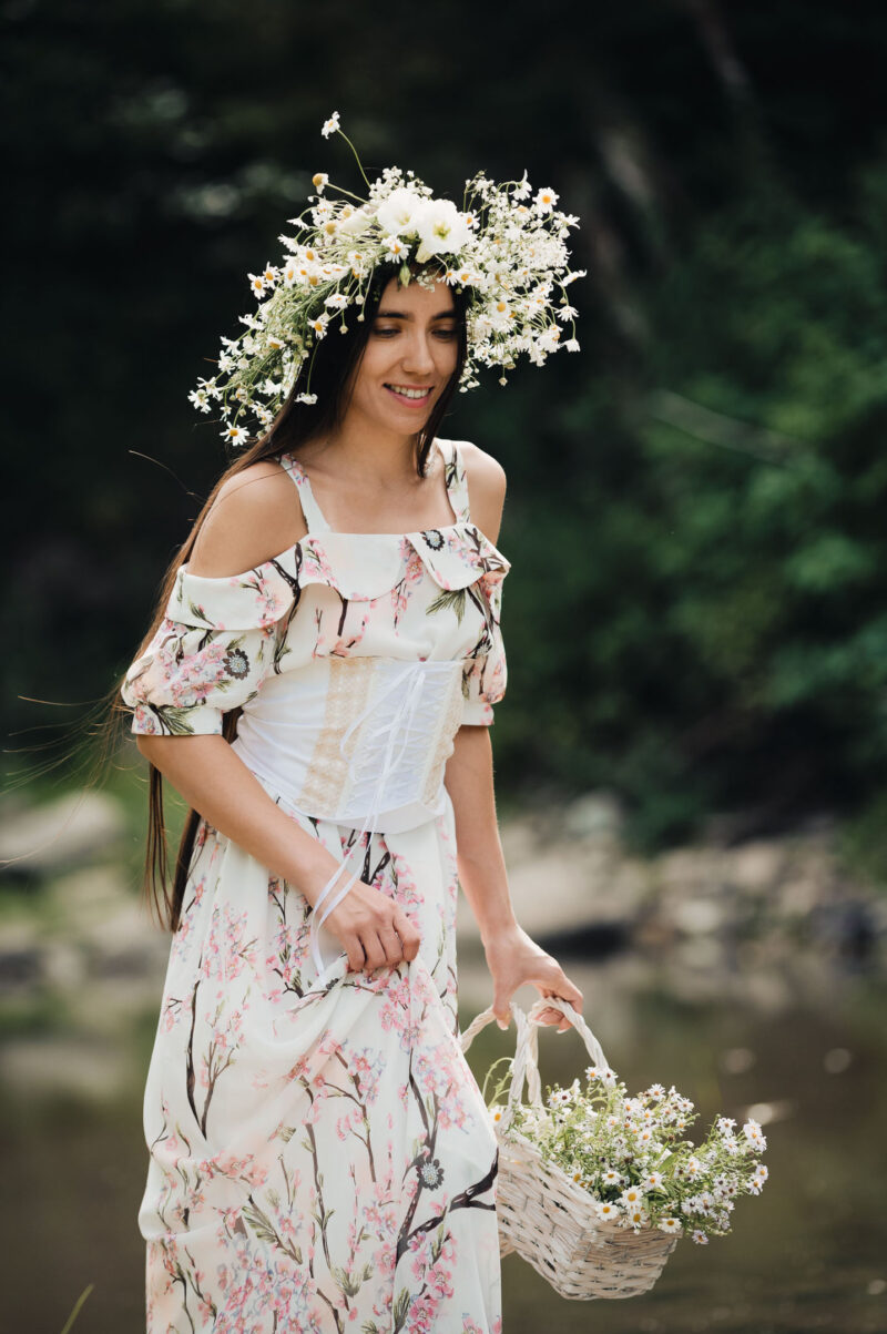 портрет девушки с венком на голове и с плетёной корзинкой в лёгком летнем платье на природе
