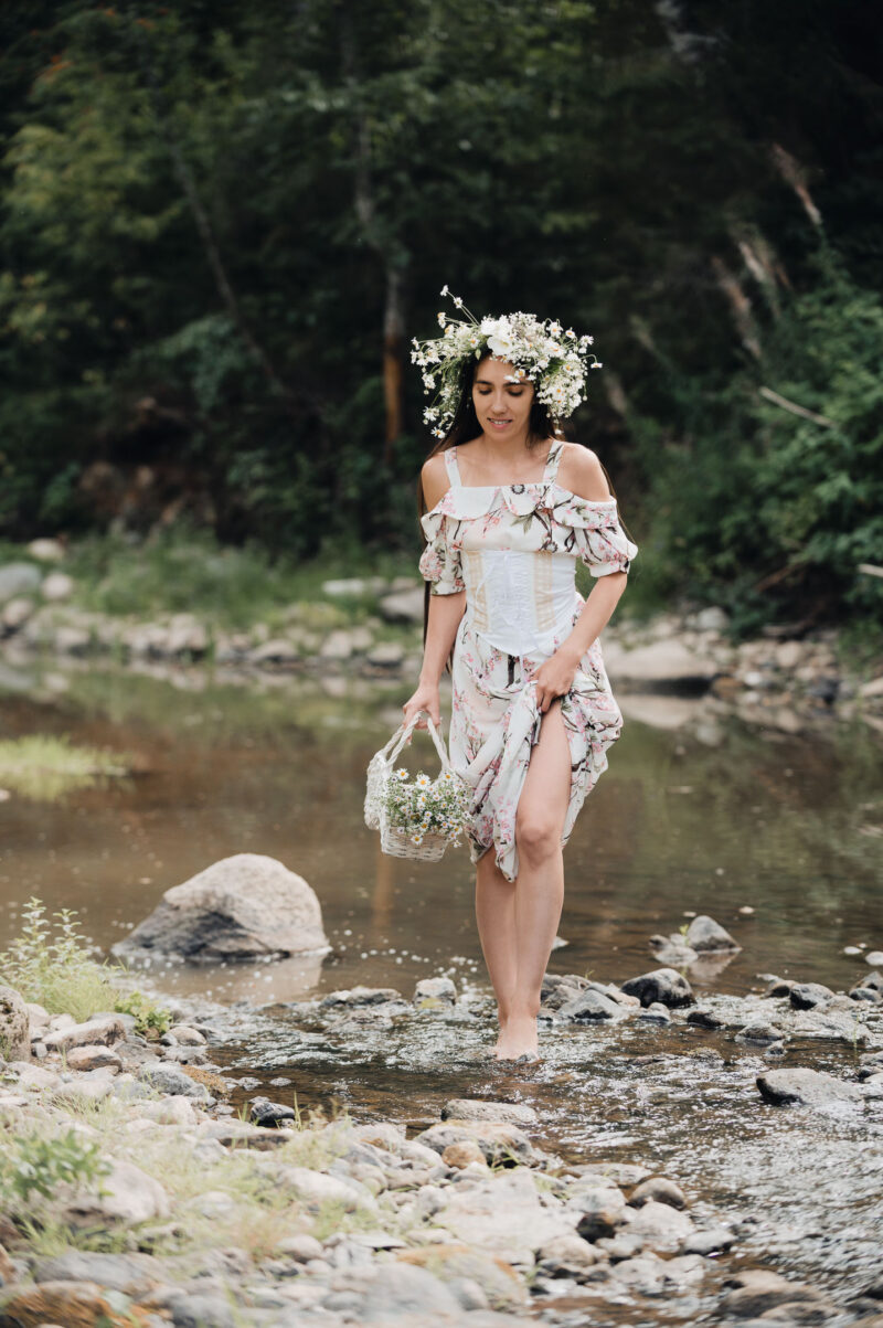 естественные эмоции девушки на природе в легком длинном платье, идущей по воде лесной реки