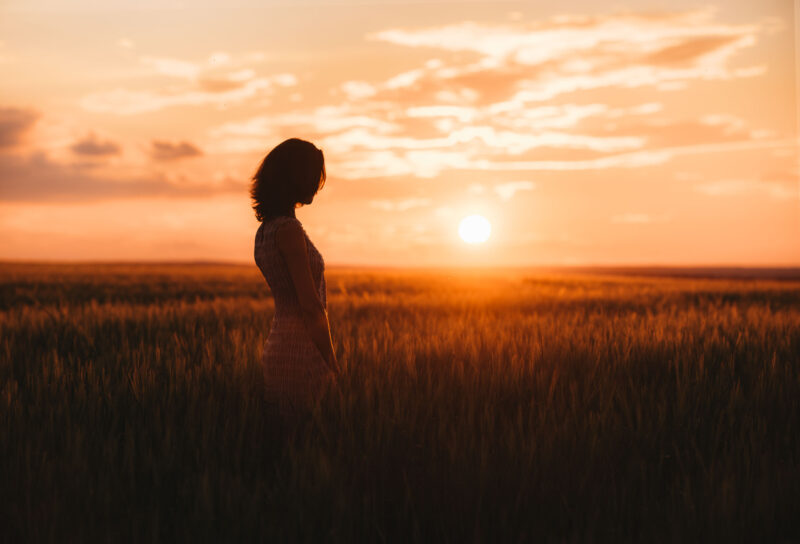 Средний план девушки, смотрящей вдаль среди колосьев в мягком вечернем освещении