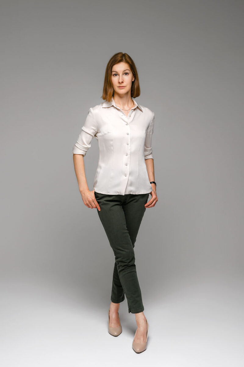 Девушка стоит в полный рост на светлом фоне фотостудии