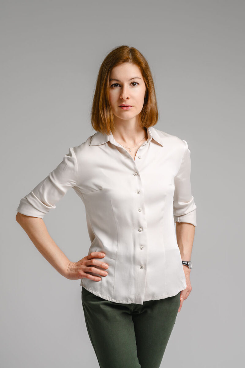 Женский портрет по пояс с рукой на талии в студийном пространстве