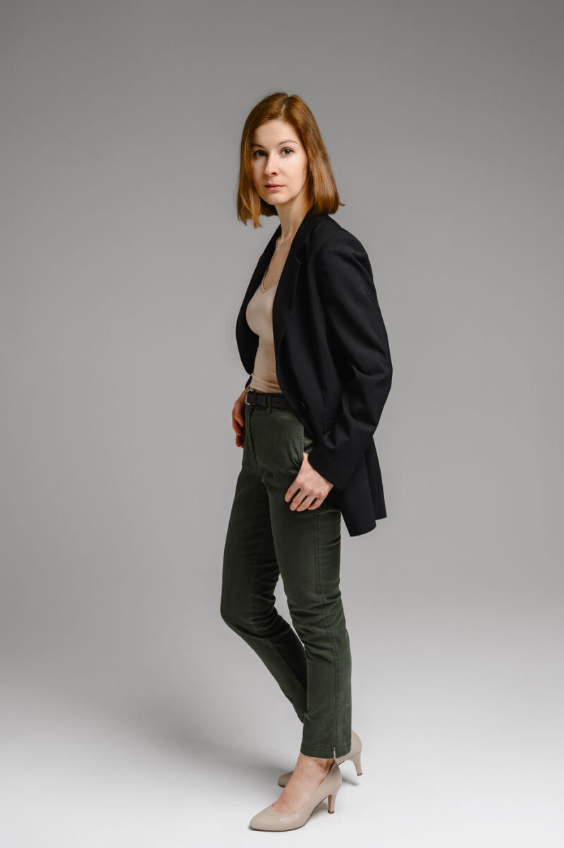 Портрет девушки в полный рост вполоборота к камере, в чёрном пиджаке