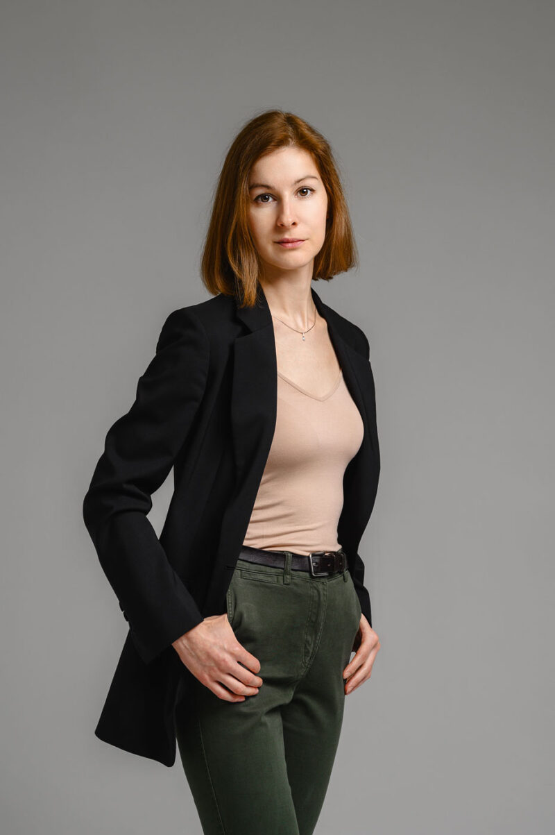 Портрет девушки по пояс в черном пиджаке и бежевом топе