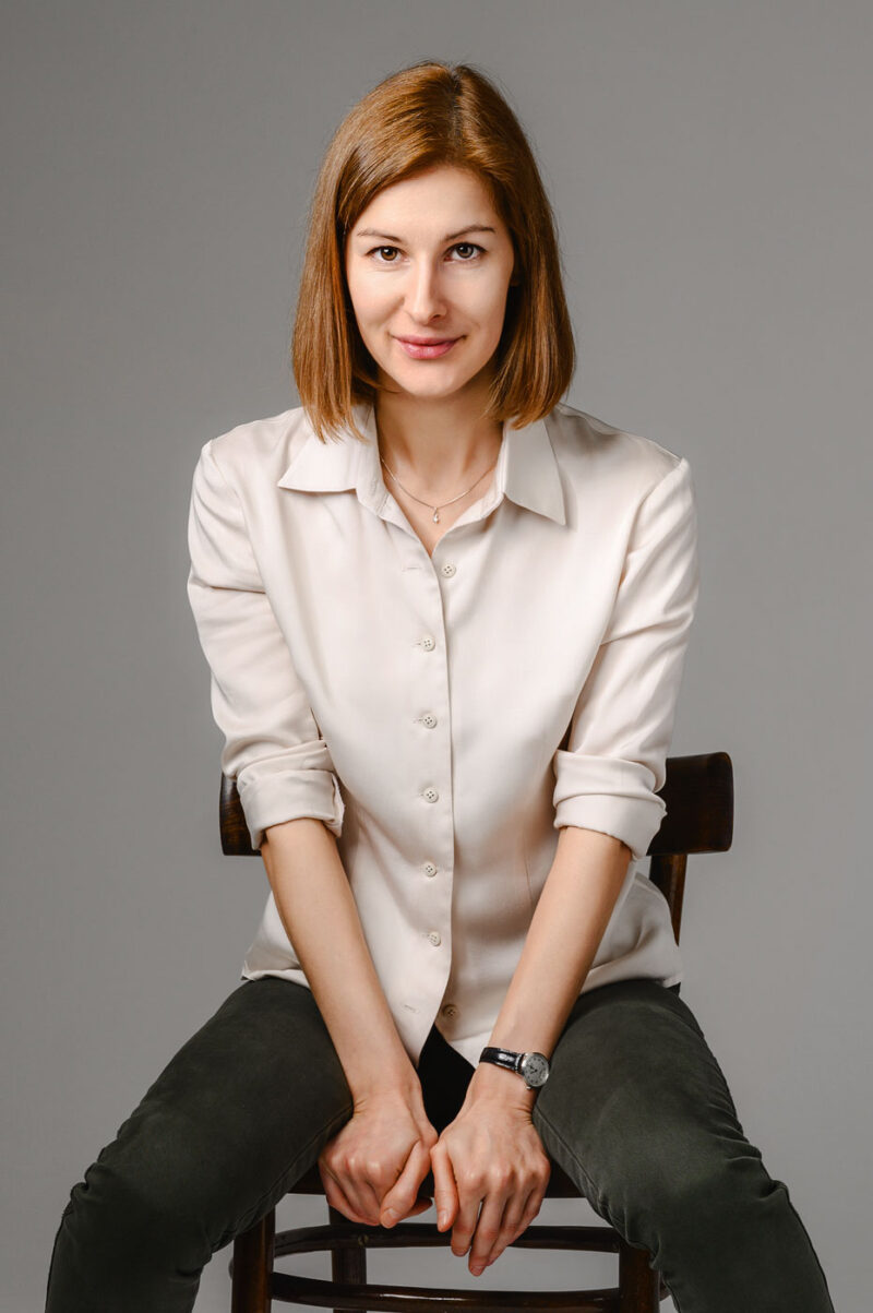 Крупный план девушки в светлой рубашке, сидящей прямо перед камерой в фотостудии