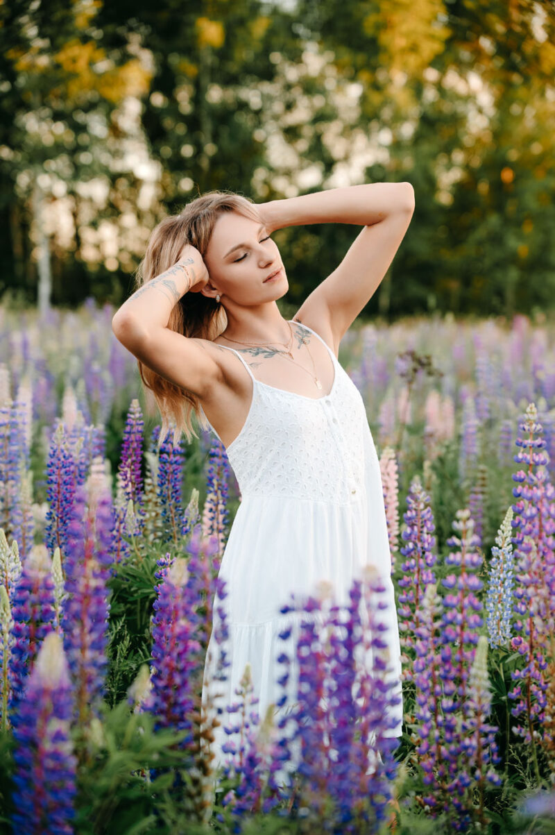 Женский портрет в белом платье на поляне среди люпинов при мягком естественном свете