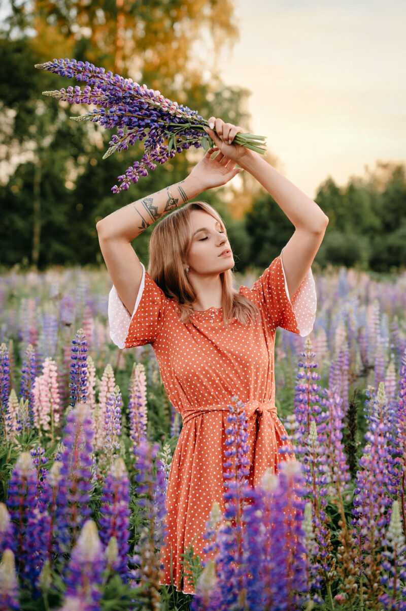 Девушка в оранжевом платье с букетом в теплом свете заходящего солнца