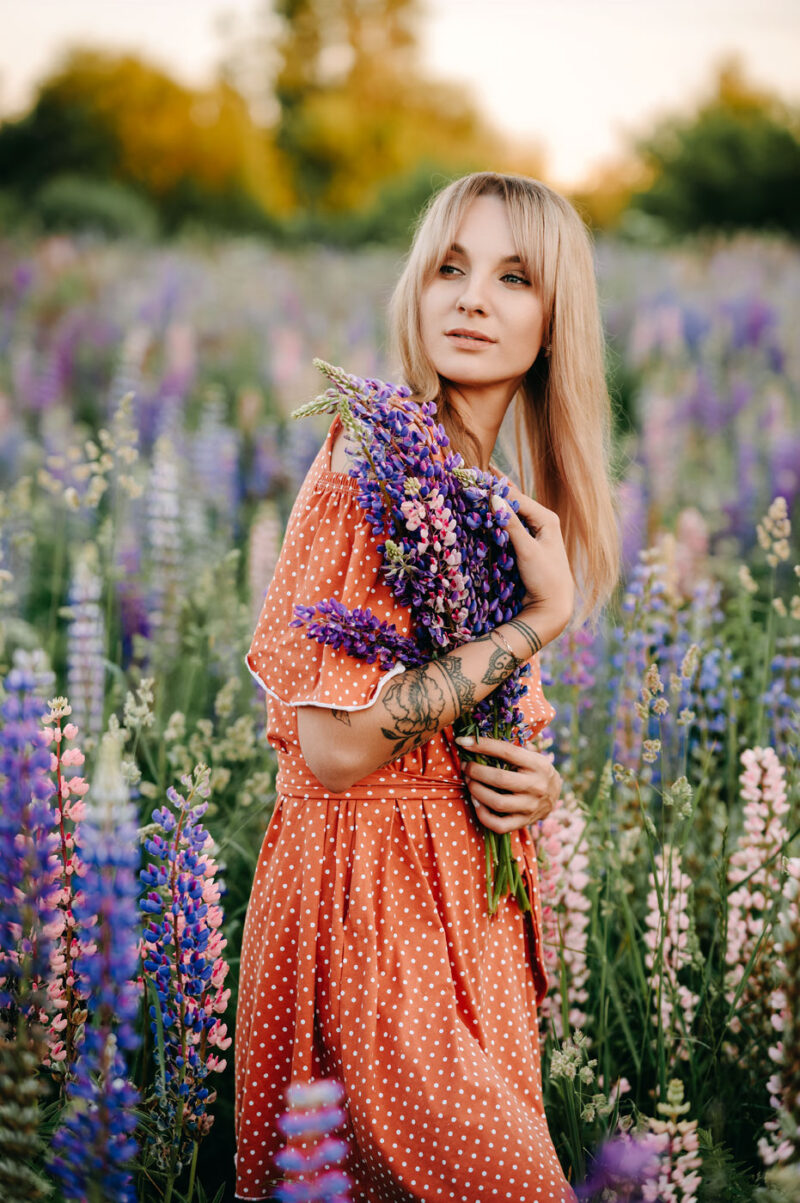 Девушка в летнем платье держит букет люпинов
