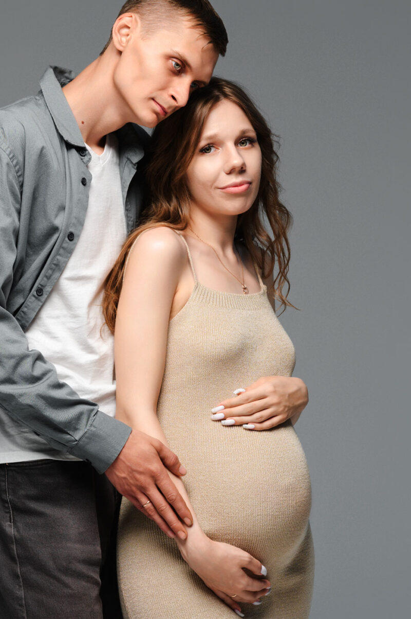 муж нежно обнимает жену на фотосессии в ожидании малыша