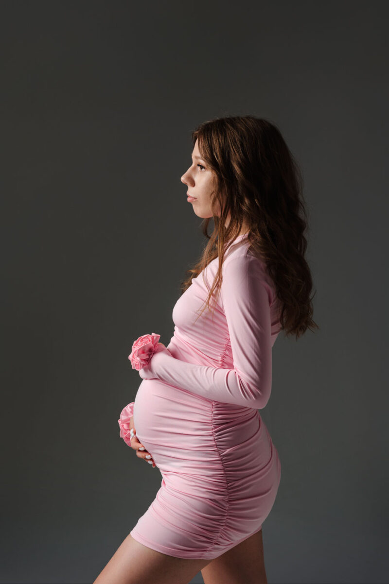 лаконичный портрет беременной на однотонном фоне, естественная поза и акцент на состоянии