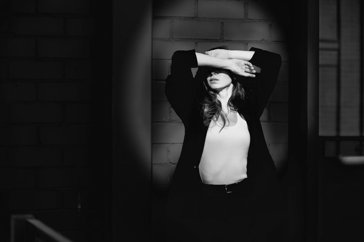 Женский портрет в низком ключе с акцентным световым пятном на фоне кирпичной кладки