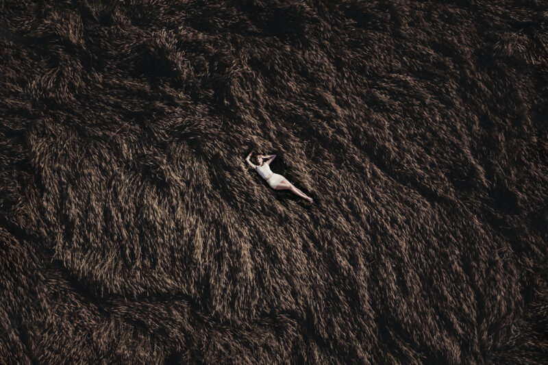 девушка, лежащая на пшеничном поле - съёмка с дрона