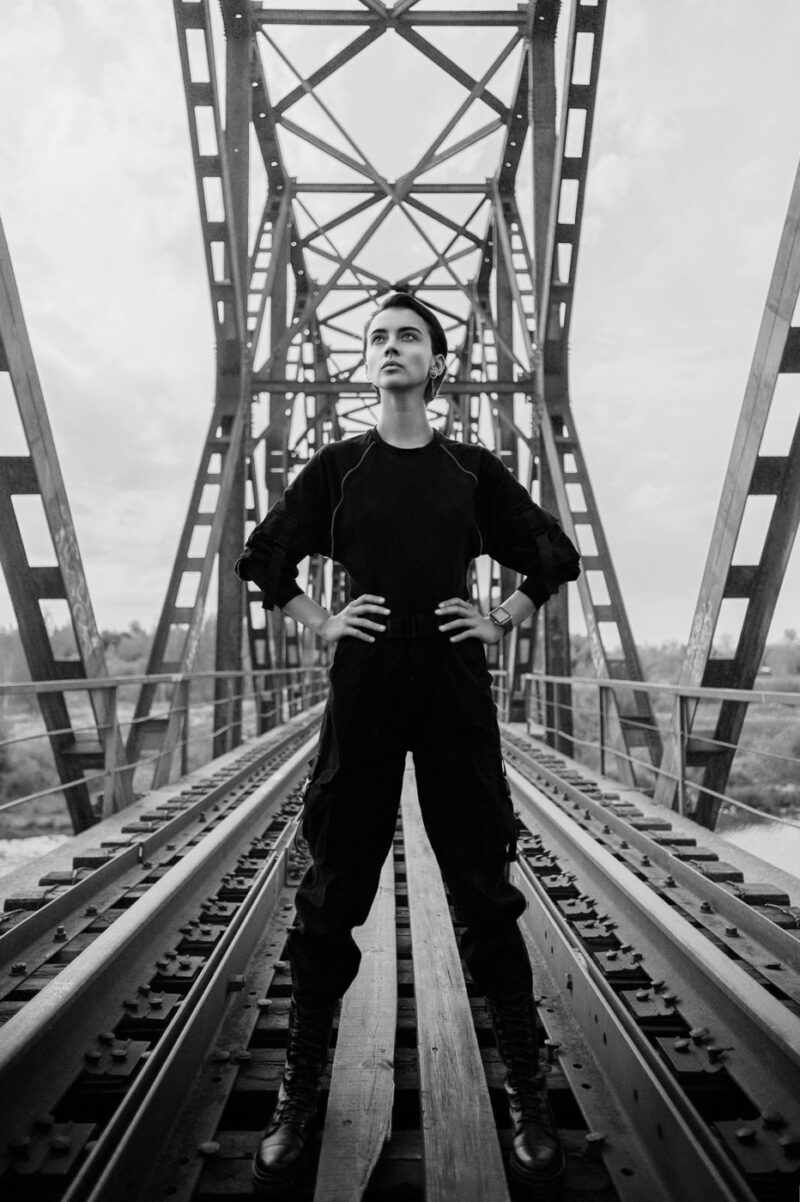 портрет девушки в чёрной одежде среди геометрии металлического моста