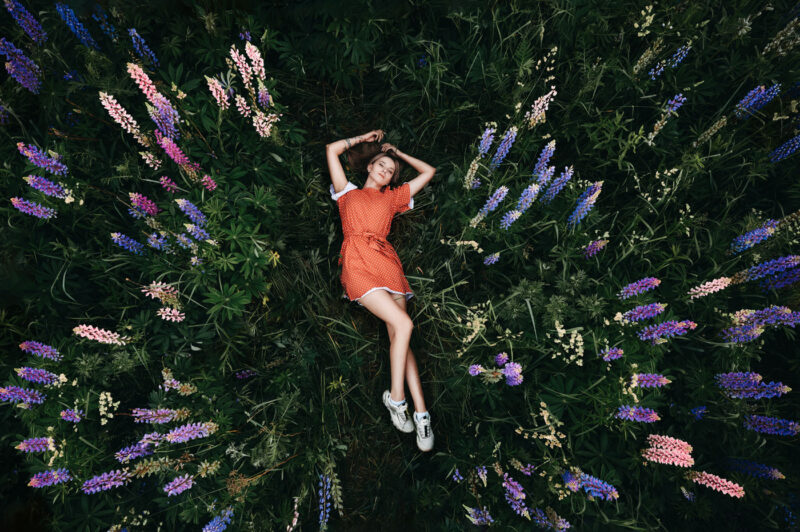 девушка лежит на поляне среди пионов