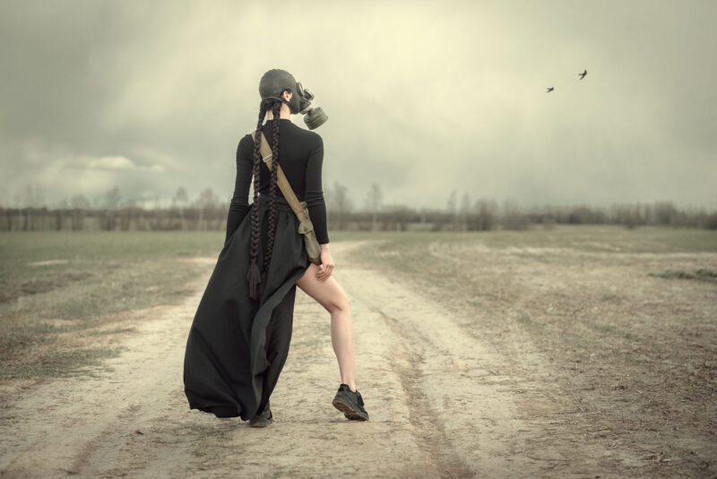 девушка в чёрном платье и с противогазом в стиле милитари стоит посреди поля - картина Постапокалипсиса